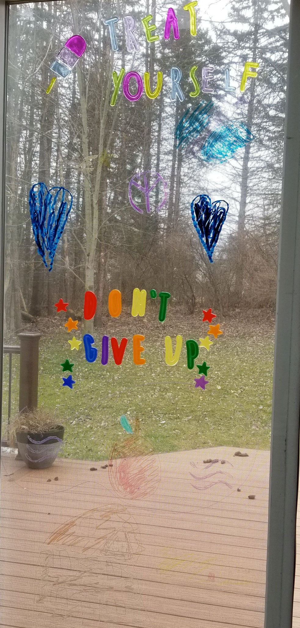 picture of window that has art that says treat yourself and do not give up